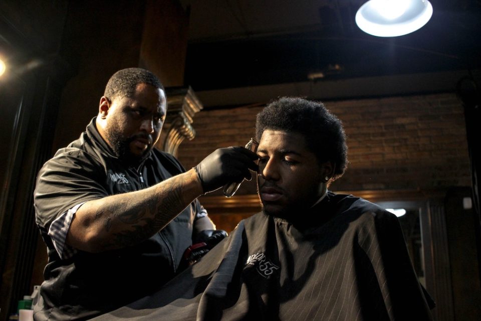 A barber cutting his customer's hair.
